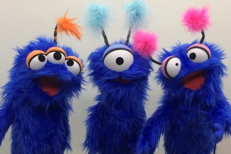 Three blue alien monster puppets. 1 with one eye, 1 with 2 eyes, and 1 with 3 eyes.