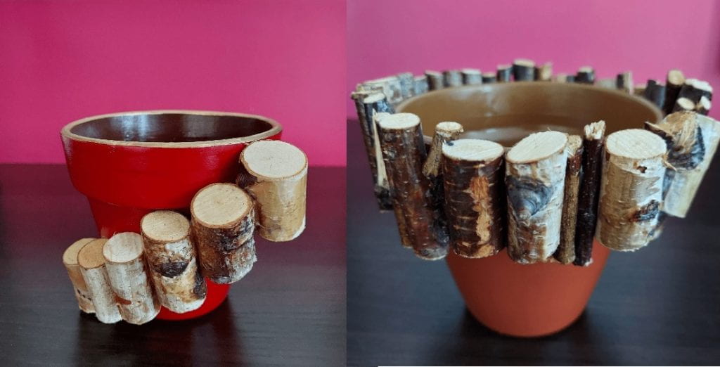 Two red teracotta pots decorated with wood, the pot on the left is adorned with wood that rises like stairs around the pot, the pot on the right has the wood wrapped around the top