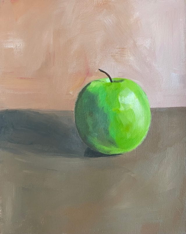 Still life of one large bright green Granny Smith apple sitting on a table. 
