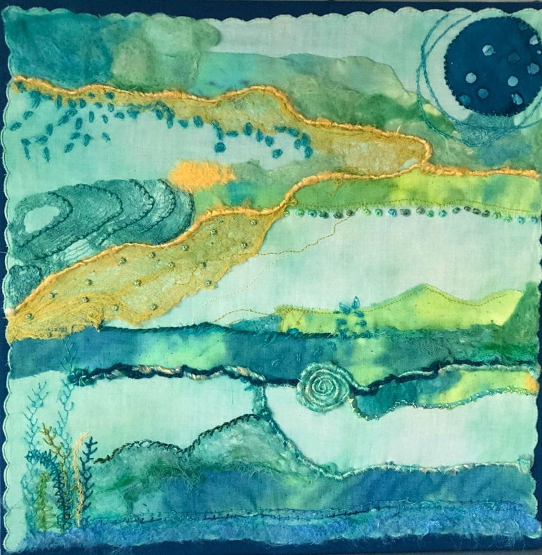Large pale blue cloth with various swatches of cloth and silk chord sewn one, as well as wool felted on, and embroidered in places. It look like an abstract marshland with the moon shining down.