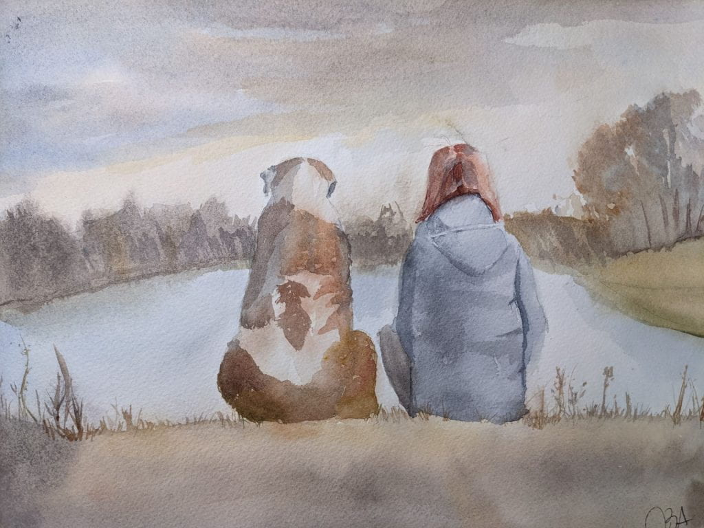 Female and large dog sitting next to each other on the edge of a pond enjoying the view.