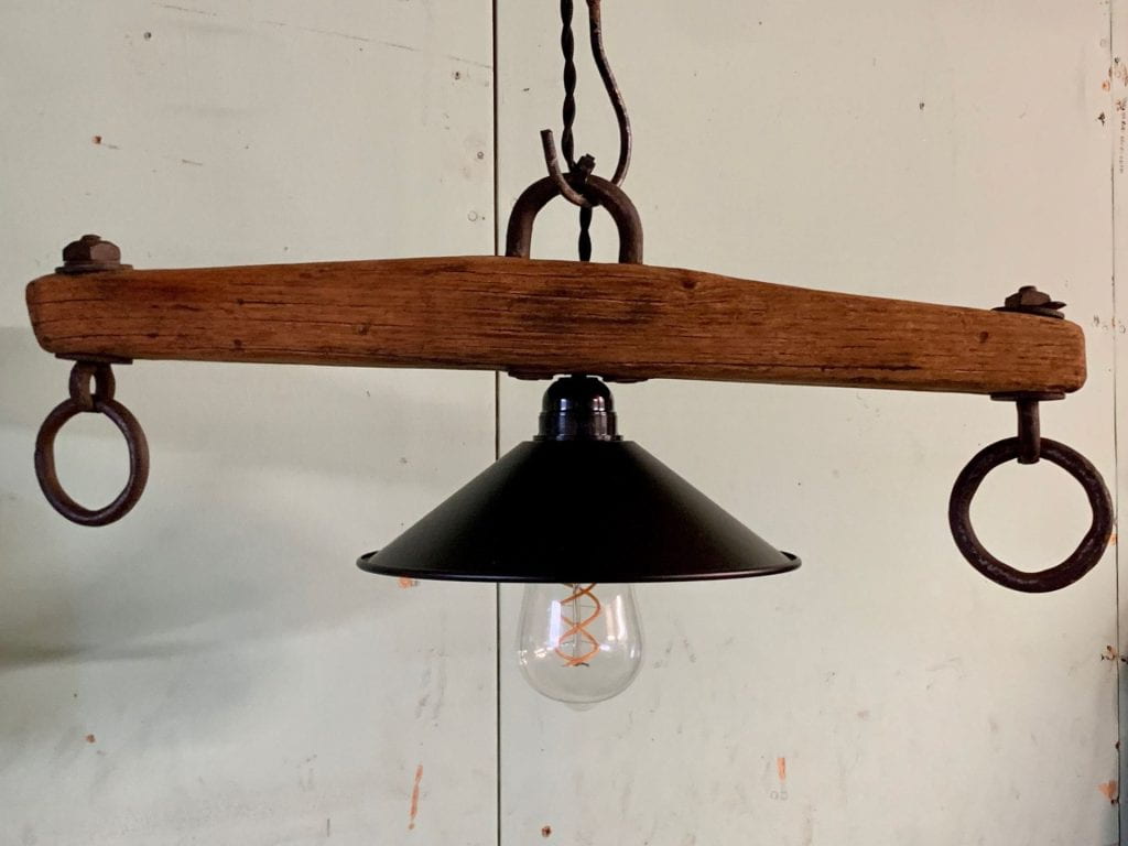 A modern light with a simple black shade and bulb with decorative filament is upcycled and incorporated into a whipple tree to make a rustic light fixture.