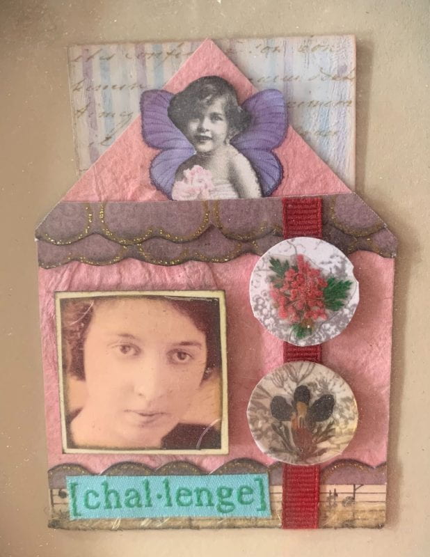 A house made of handmade paper, with images of a woman's face, two round medallions, and a young girl with purple butterfly wings. The word "challenge" is pasted along the bottom over a strip of vintage sheet music.