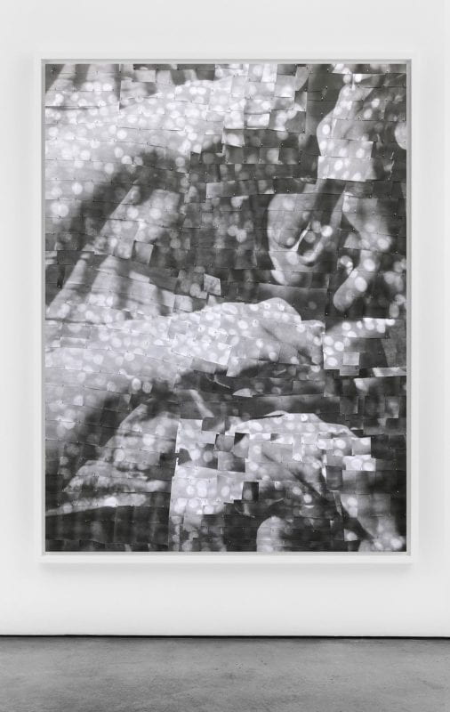 A mosaic of black and white squares cut from photographs and pinned into foam makes a larger image, an abstraction with dots of light and subtle gestures of hands making shapes.