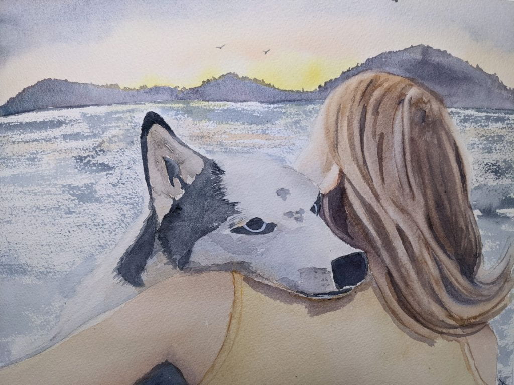 Woman hugging her husky on the ocean shore, watching the sunrise.