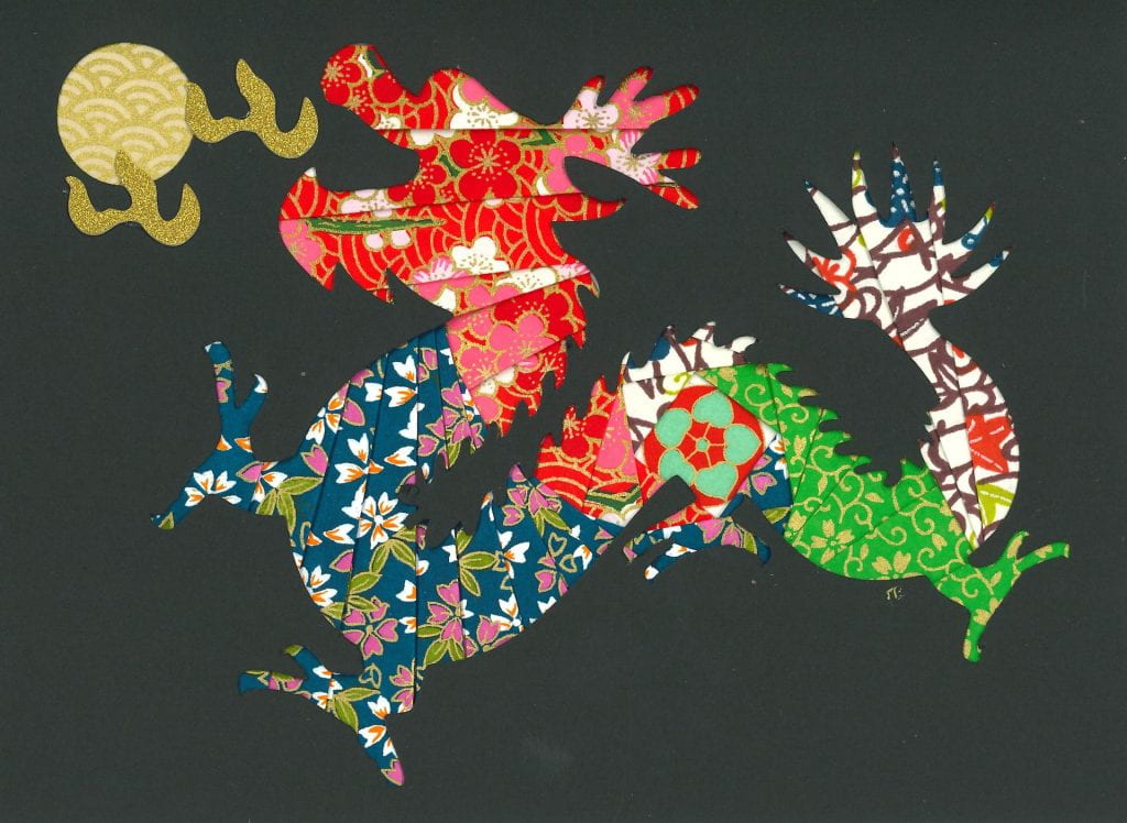 Different papers with colorful patterns of flowers and geometrical shapes compose a dragon breathing fire under a full-moon shaped pearl. The dragon head is red and gold, the background is black.