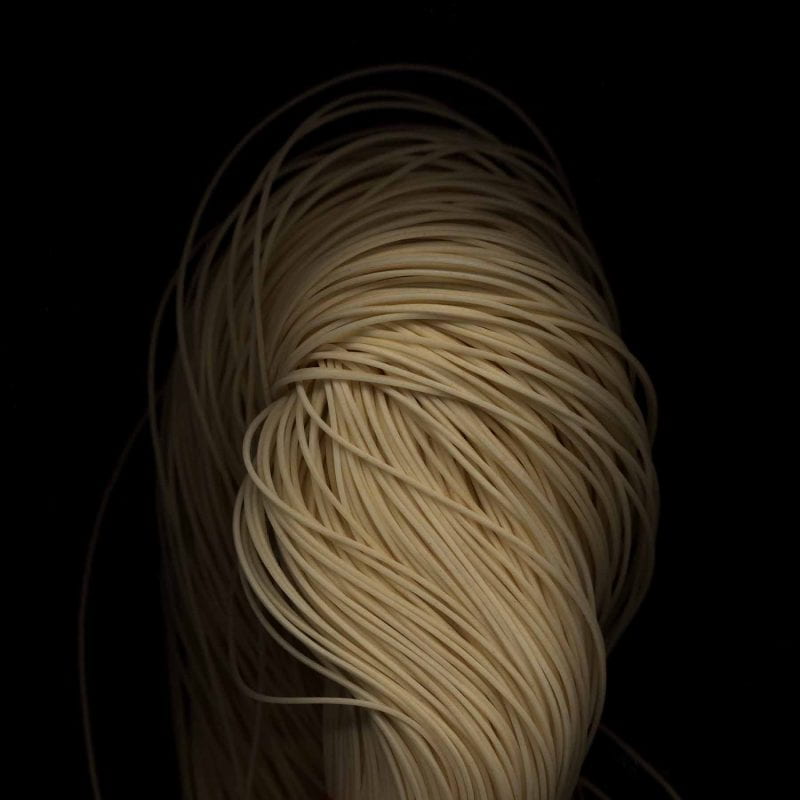 Chinese wheat noodles illuminated against a dark backdrop.