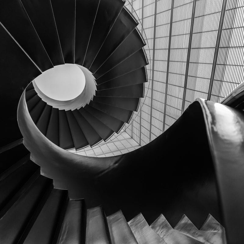 Black and white photo of metal spiral staircase taken from base of stairwell looking up.