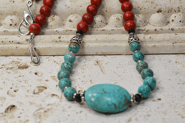 Necklace made with natural turquoise and red sponge coral beads, adorned with faceted black onyx beads and sterling silver accents.