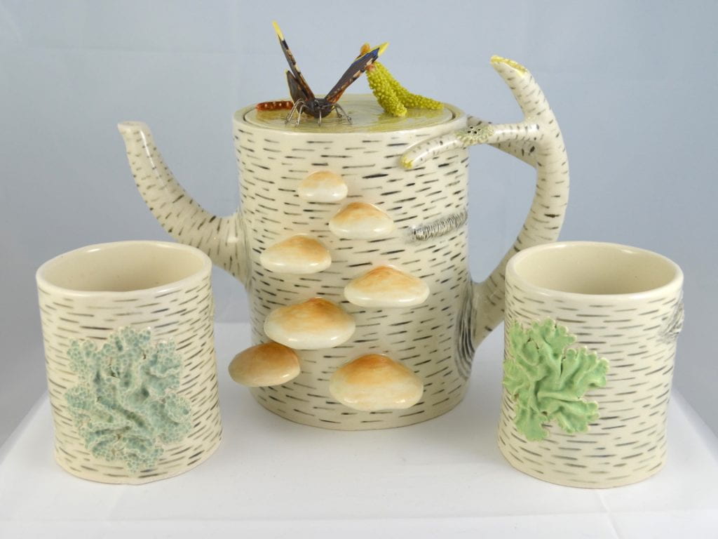 Teapot and two cups textured like birch bark, with mushrooms and patches of lichen.