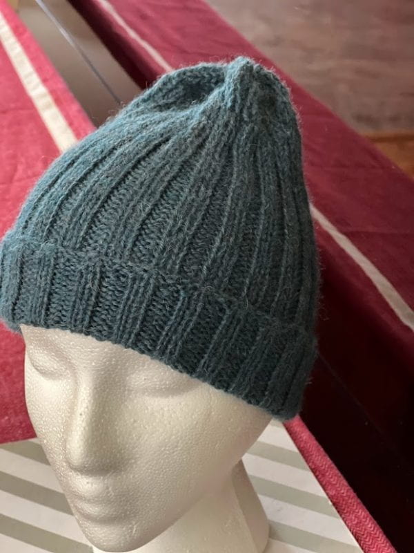 A turquoise knitted winter hat on a mannequin's head.