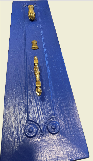 Carved blue wooden board with antique and vintage brass hardware representing a historic Aegean island door.