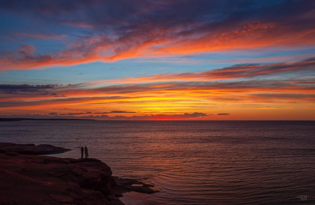 Couple enjoying a spectacular sunset over Gulf of St. Lawrence from Cavendish Beach, in PEI National Park, Canada.
