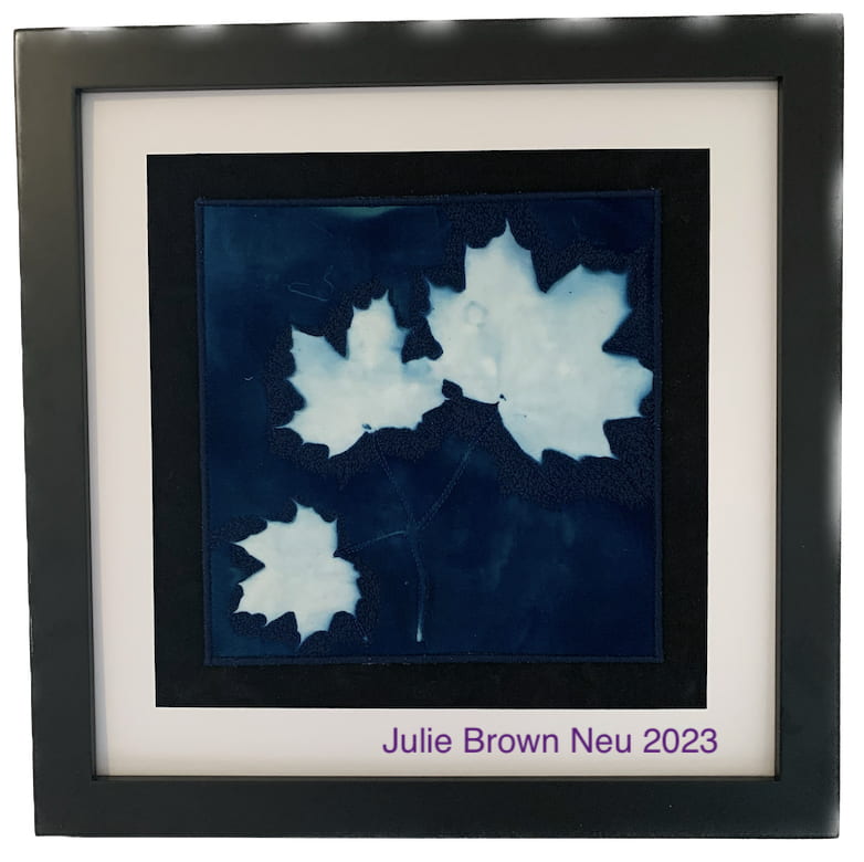 Cyanotype of three small white maple leaves on a blue background.