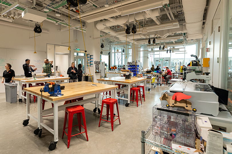An interior view of the SEAS Makerspace displaying workstations, machinery, and people in the background